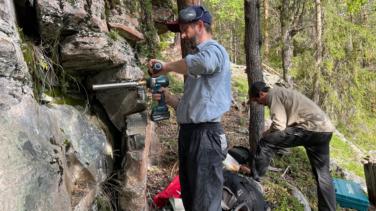 Photo of 2 scientists sampling a rock outcrop.
