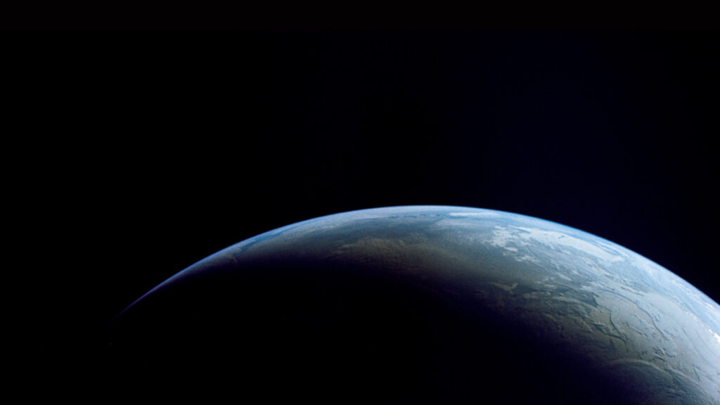 A view of Earth from space fills the bottom third of the image. Above is the blackness of space.