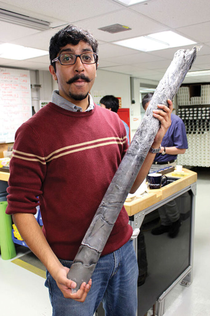 Kaustubh Thirumalai holds a sediment core on the JOIDES Resolution.