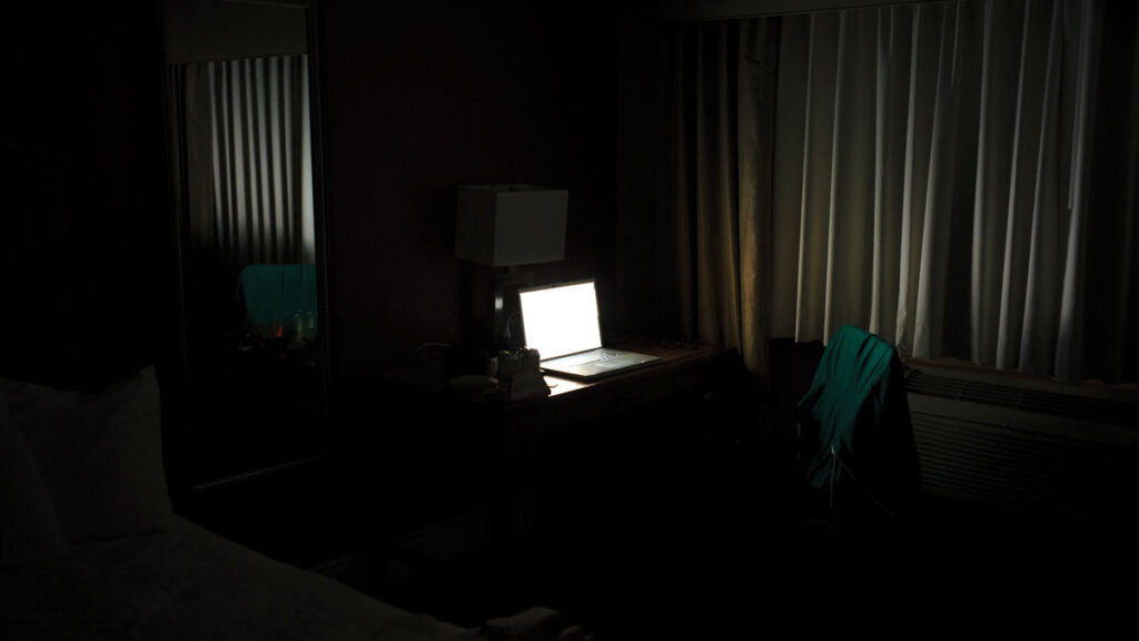 Illuminated laptop computer on desk in darkroom at office