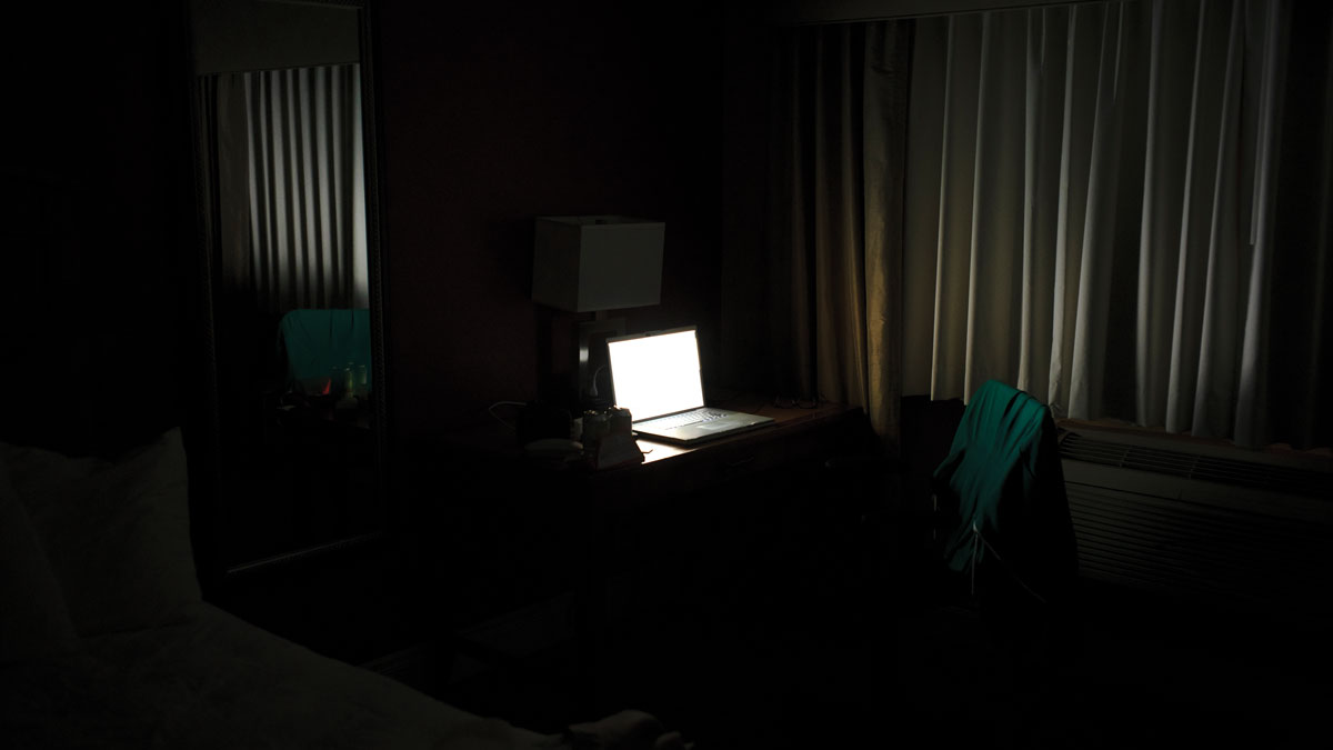 Illuminated laptop computer on desk in darkroom at office
