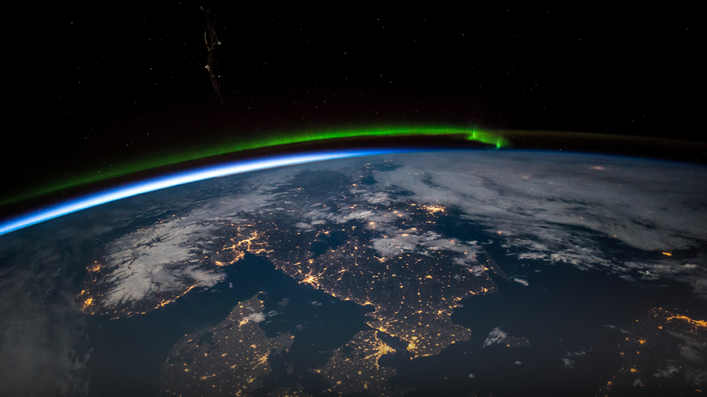 Aerial view from above Earth showing Scandinavia at night. Green aurora above the northern Baltic Sea.