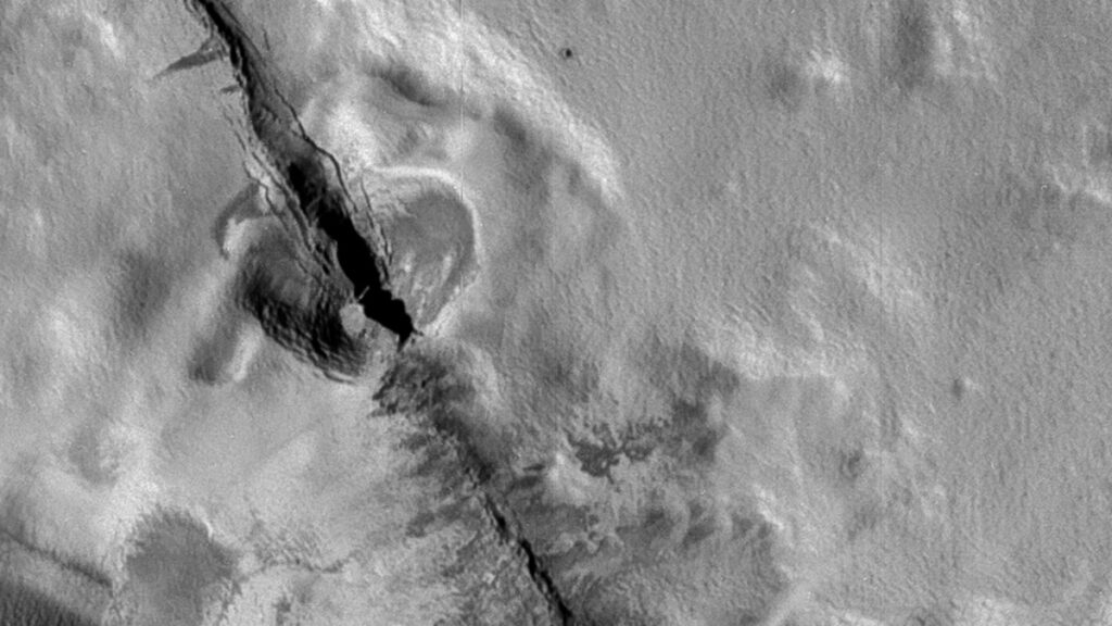 The mountain Telegonus Mensae on Io. In the bottom center of the image is a dark spot that could be an impact crater.