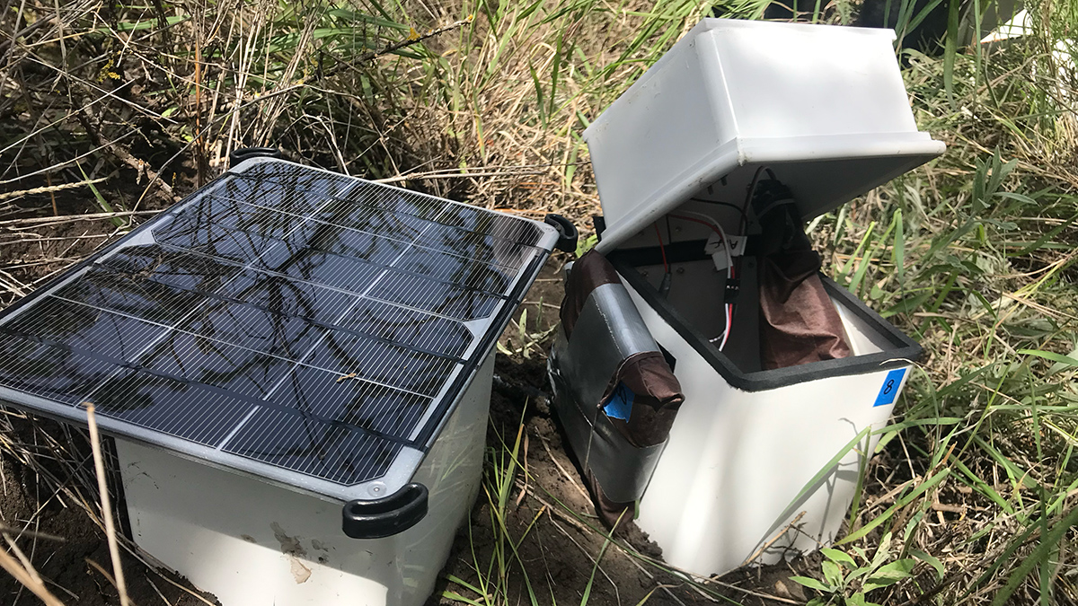 A fluxbot, a small white box containing wires and a piece attached with duct tape. A solar panel is next to it.