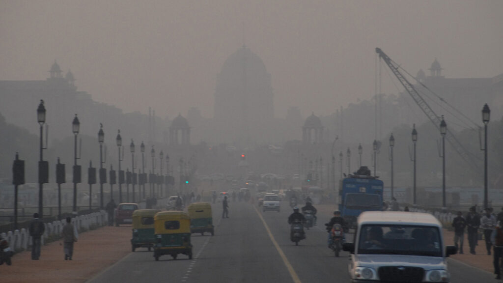 A city street with buildings in the background barely visible through smog.