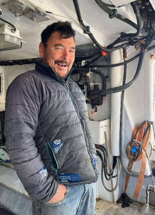 Joey Angnatok stands aboard a boat with his hands in his pockets.