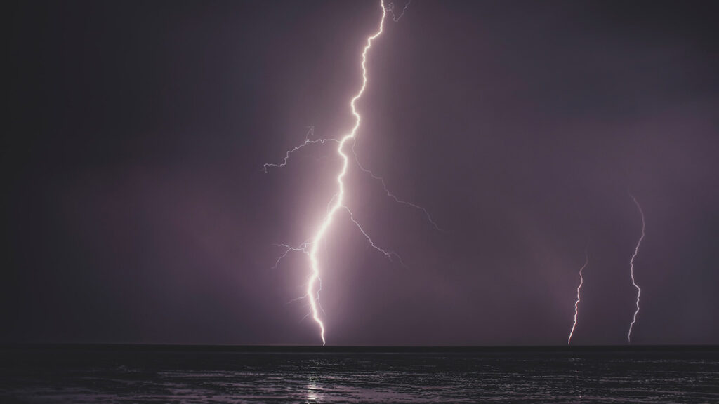 A large bolt of lightning strikes the ocean.