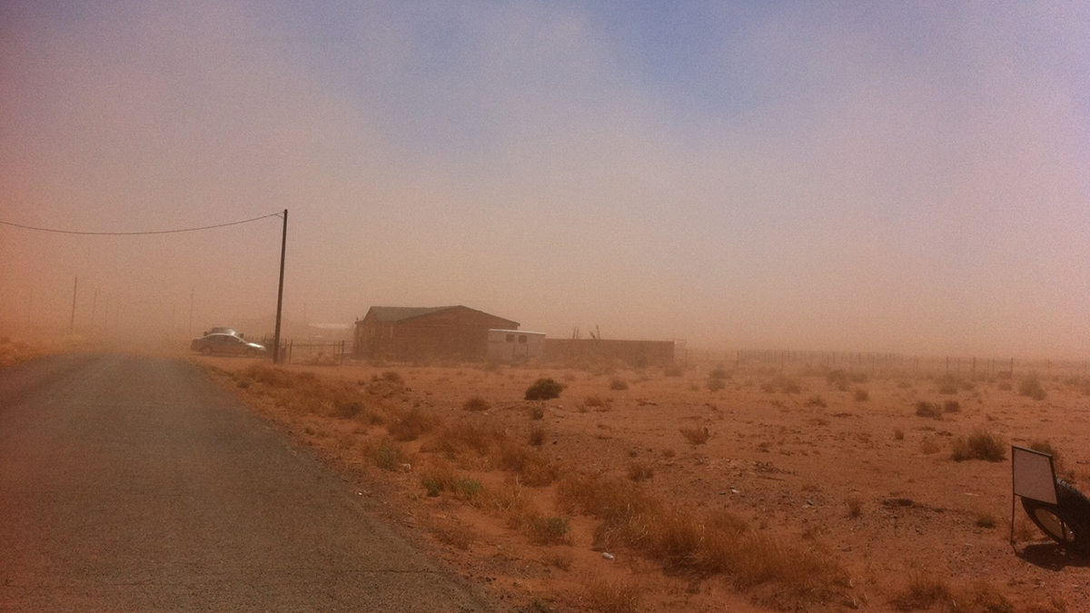 Photo of a dust storm hitting a home in an arid region.