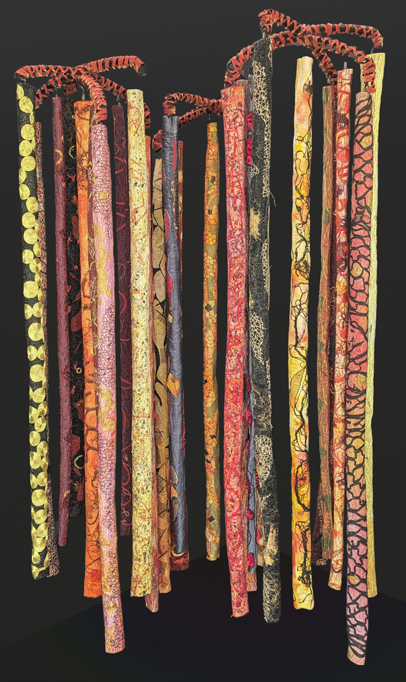 Textile art depicts lava tubes in red, orange, yellow, and black hanging from red and black fixtures.