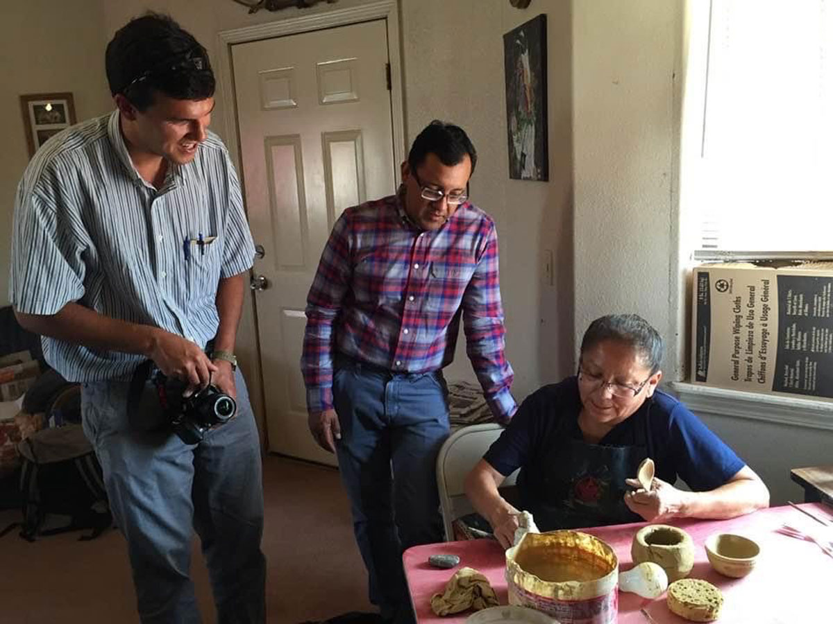 Researchers and a Navajo Nation potter discuss creating water filtration tools over a table with pottery.