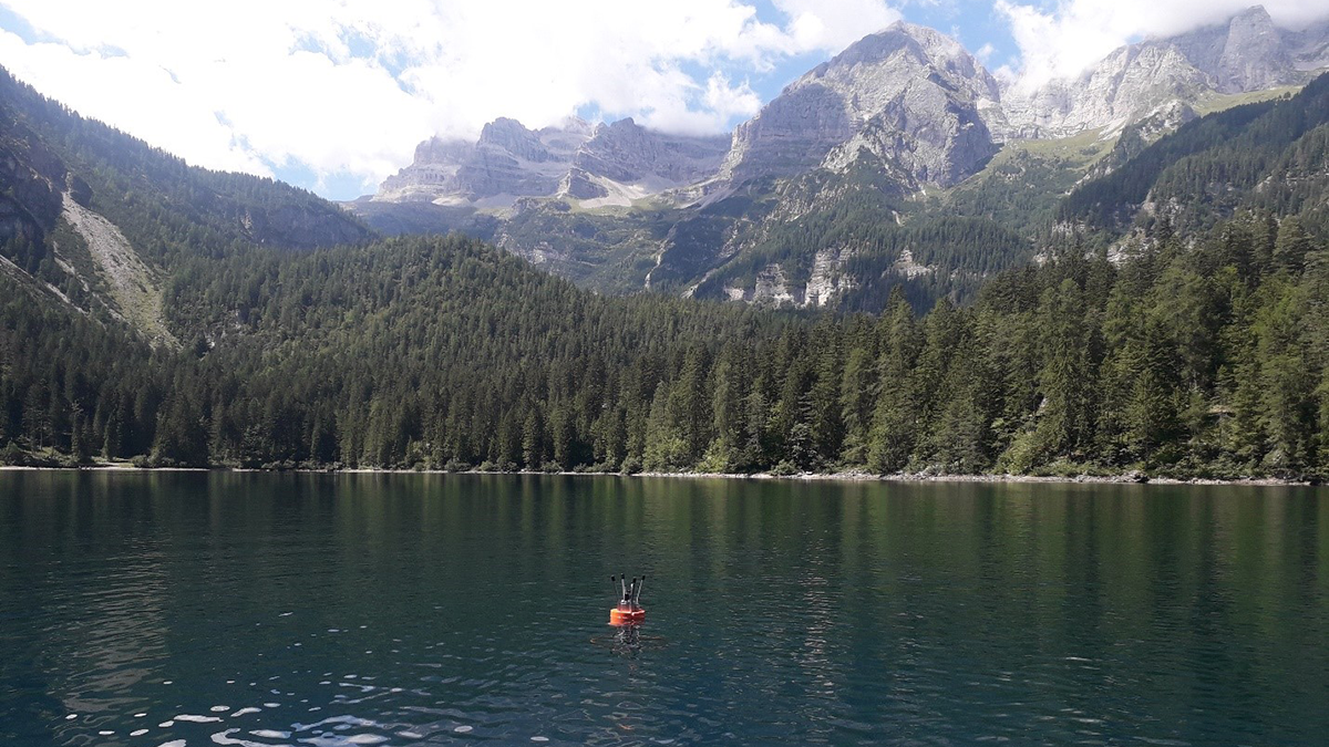 Photo of a lake with with a monitoring devise floating in the middle.