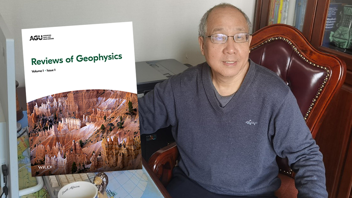 Photo of Qingyun Duan in his office with a cover of Reviews of Geophysics.