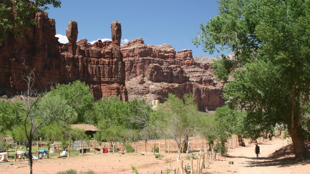 A small village in a canyon surrounded by tall, red cliffs