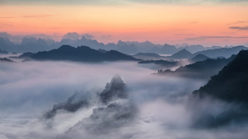 Fog settles in between mountain peaks at sunset.