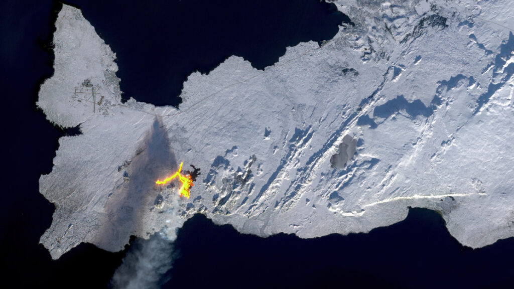 A satellite image looking down at snow-covered Reykjanes Peninsula with an erupting volcanic fissure and steam plume.