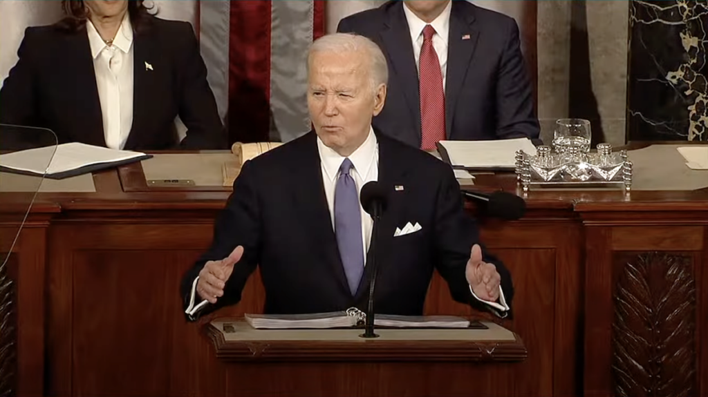 President Biden stands at the podium on the House floor, delivering his 2024 State of the Union address.
