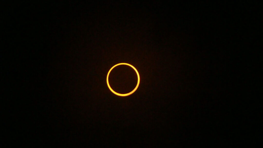 A ring of yellow light in an otherwise black sky.