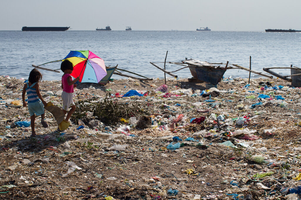 Plastic trash litters the beach as children play in Manila.