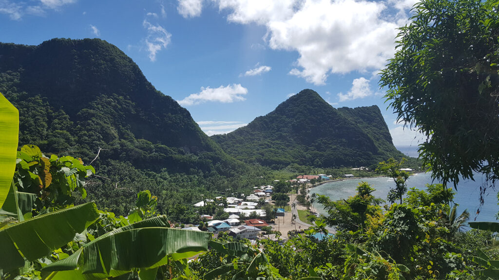Houses and roads in a shallow bay with green mountains in the background