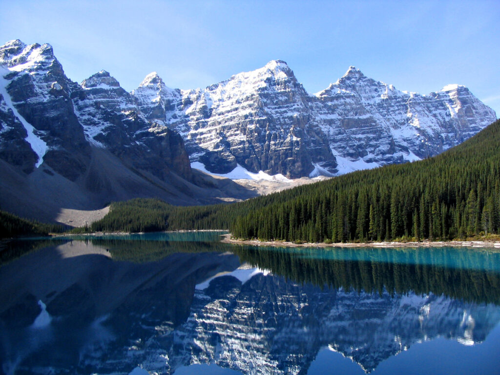 View of layered mountains with snow cover and a lake in foreground