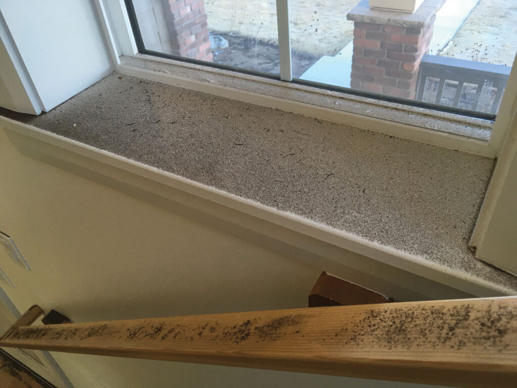Black soot accumulated on a windowsill and banister.