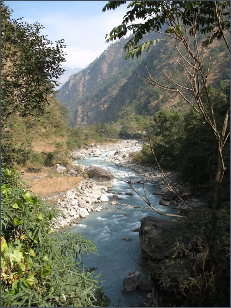 A narrow stretch of the Marsyangdi River in Nepal winds between steep forested mountain slopes.