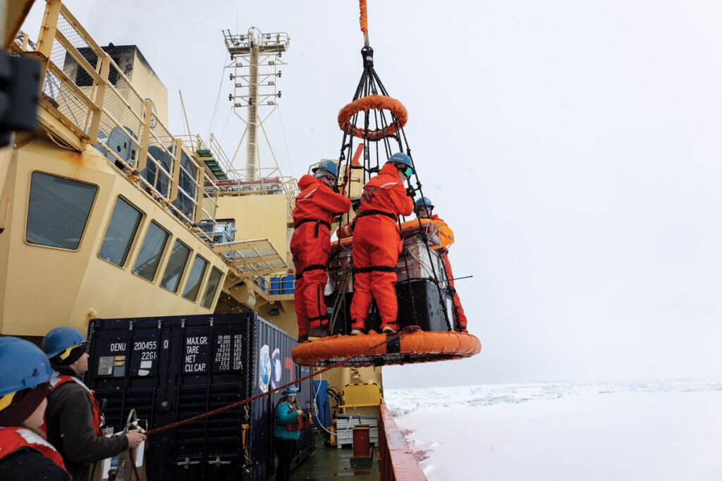 Scientists and their equipment are lowered to the sea ice by a crane.