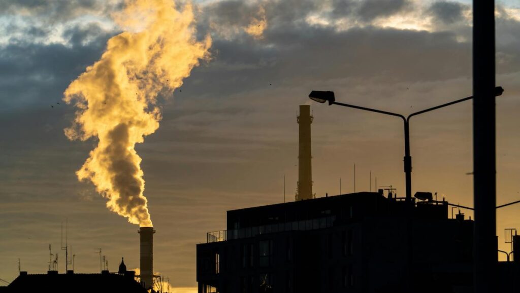 Smokestacks emit clouds of gas at sunset.