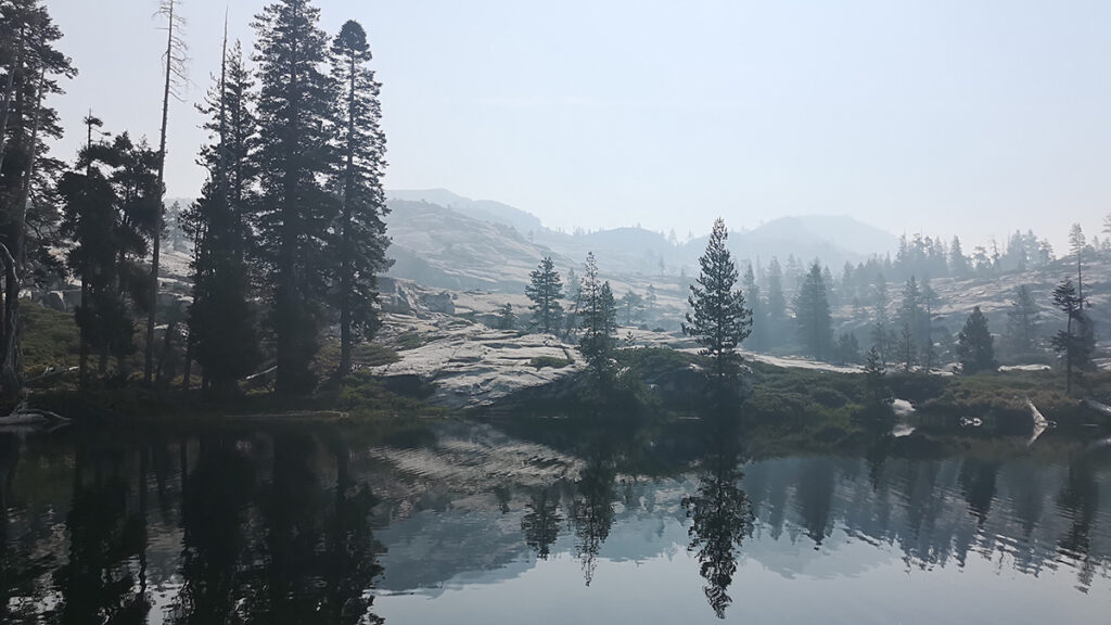 A lake surrounded by trees on a smoky day