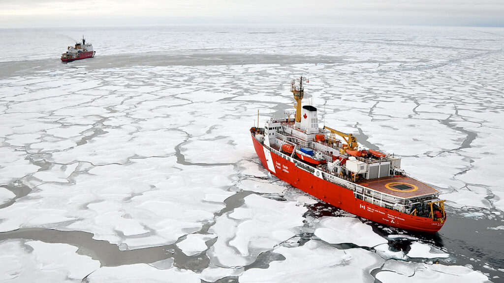 A red and white ship on an icy ocean is headed toward another ship with the same colors in the distance.