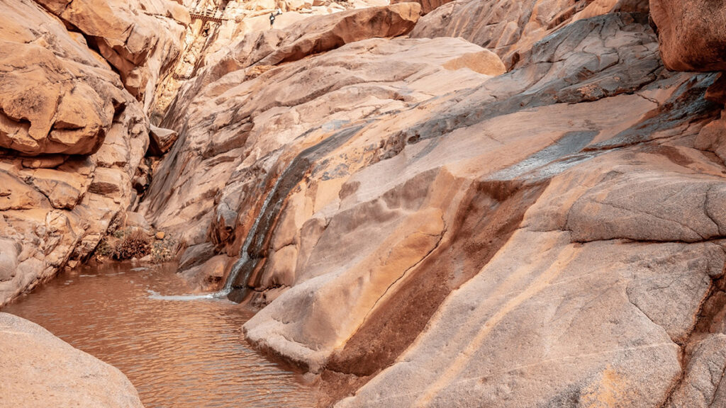 A stream in a rocky, high-walled brown desert