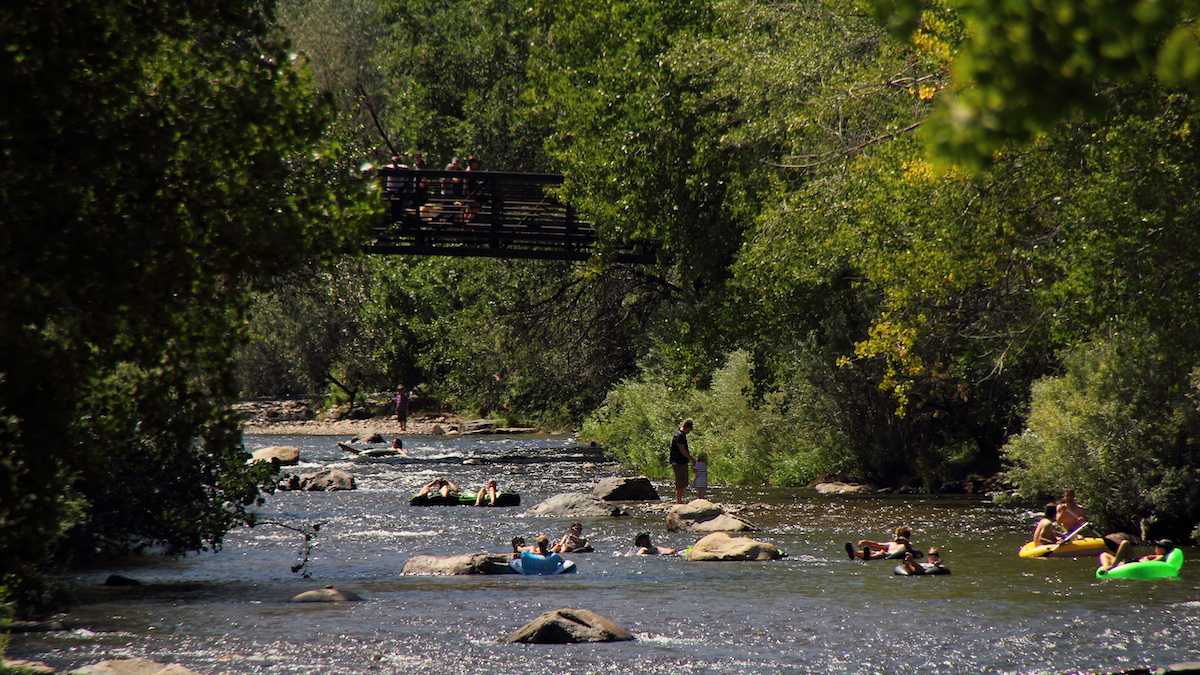 People floating in colorful tubes in the distance down gentle river rapids.