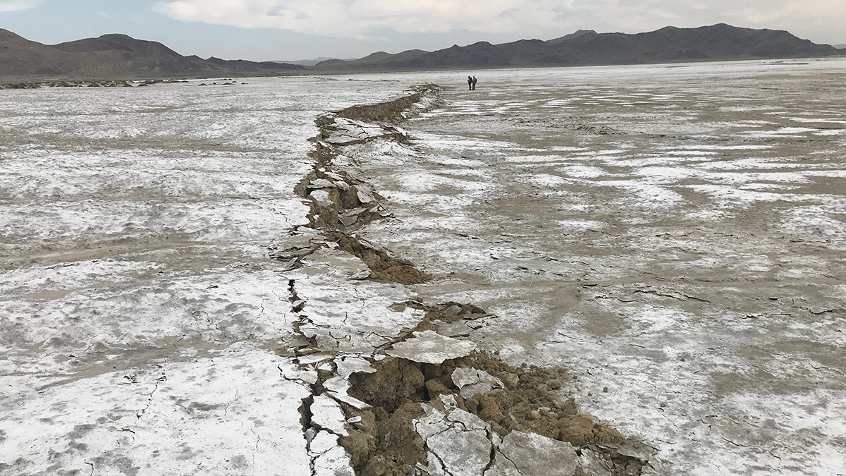 Photo of a long line of cracked earth within a mountain valley.