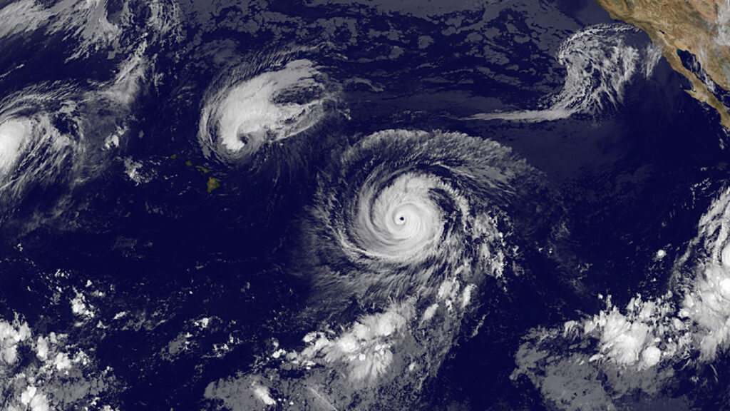 A satellite image of four tropical cyclones with pinwheel shapes forming in the Pacific Ocean