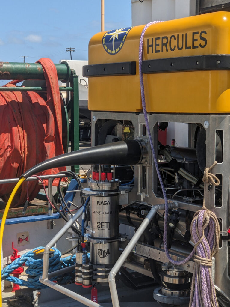 The In-situ Vent Analysis Divebot for Exobiology Research, InVADER, is seen here mounted to a remotely operated vehicle (ROV), which is sitting on the deck of a ship.