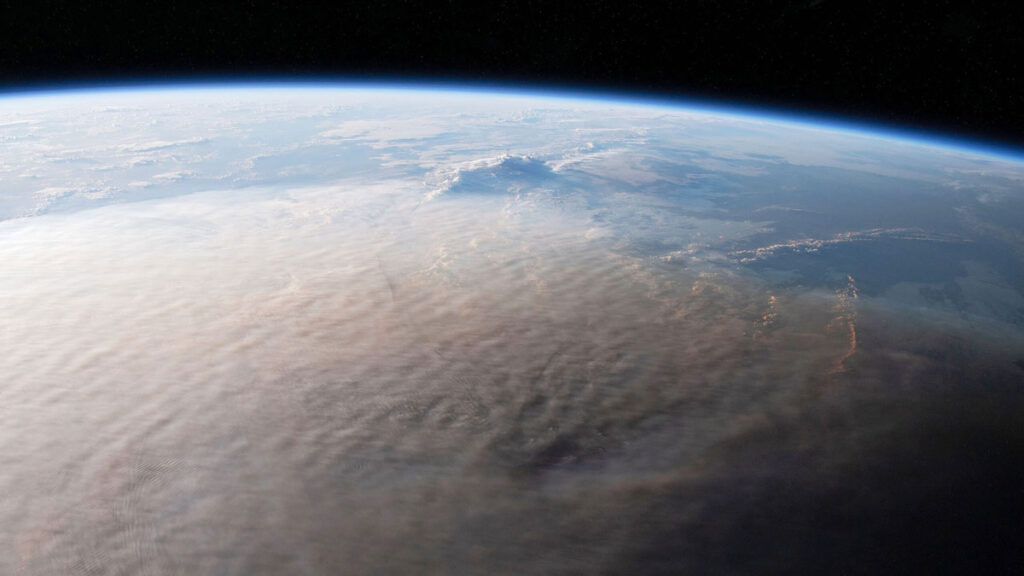 In a photo taken from space, a brown volcanic ash plume from the Hunga Tonga–Hunga Ha‘apai undersea volcano spreads out over the ocean.