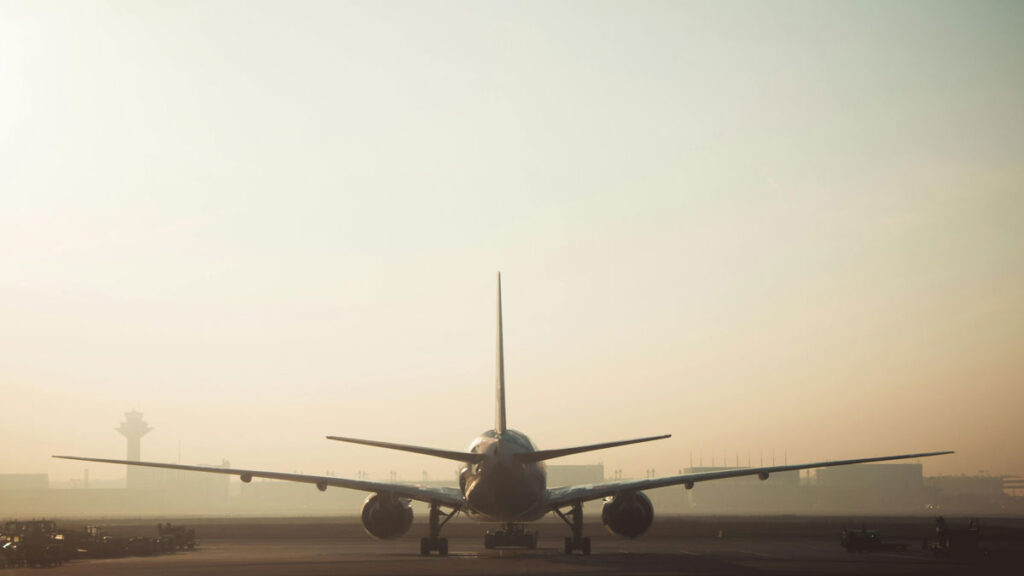 A jet airplane at an airport in hazy conditions