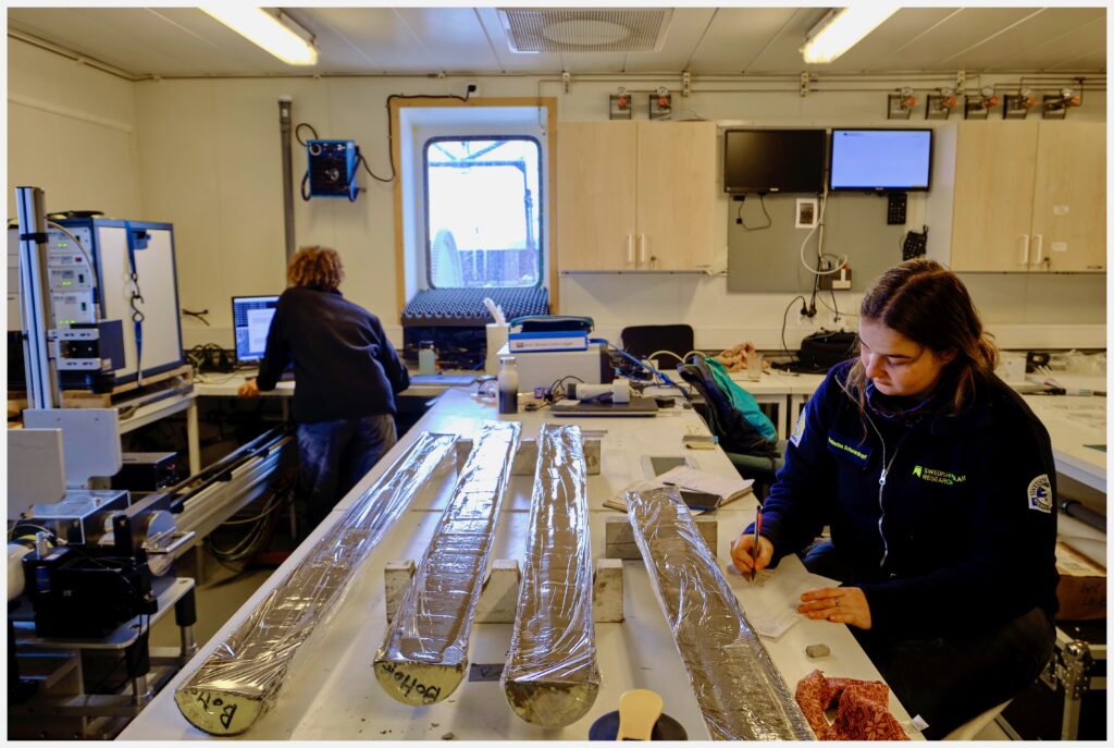 Two scientists analyze sediment cores in a laboratory.