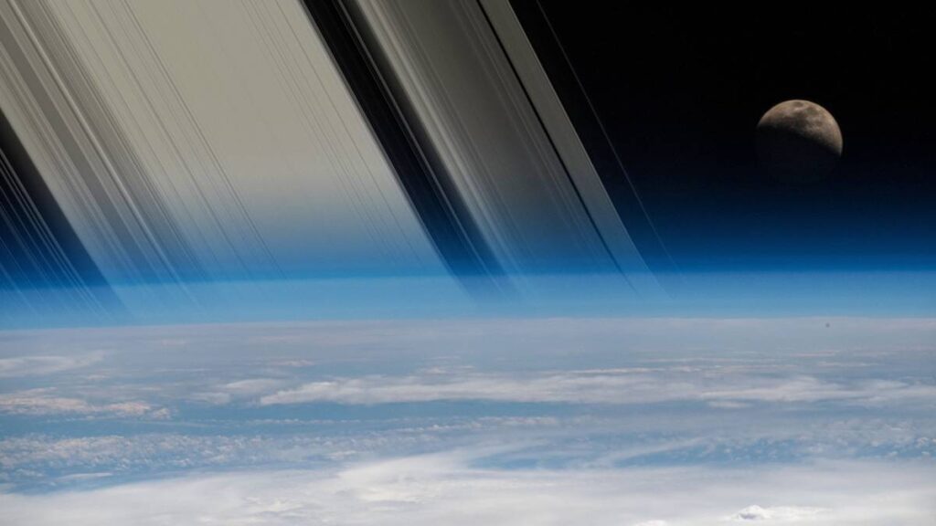 Image manipulation of Earth and the Moon seen from orbit with Saturn’s rings disappearing behind the horizon.