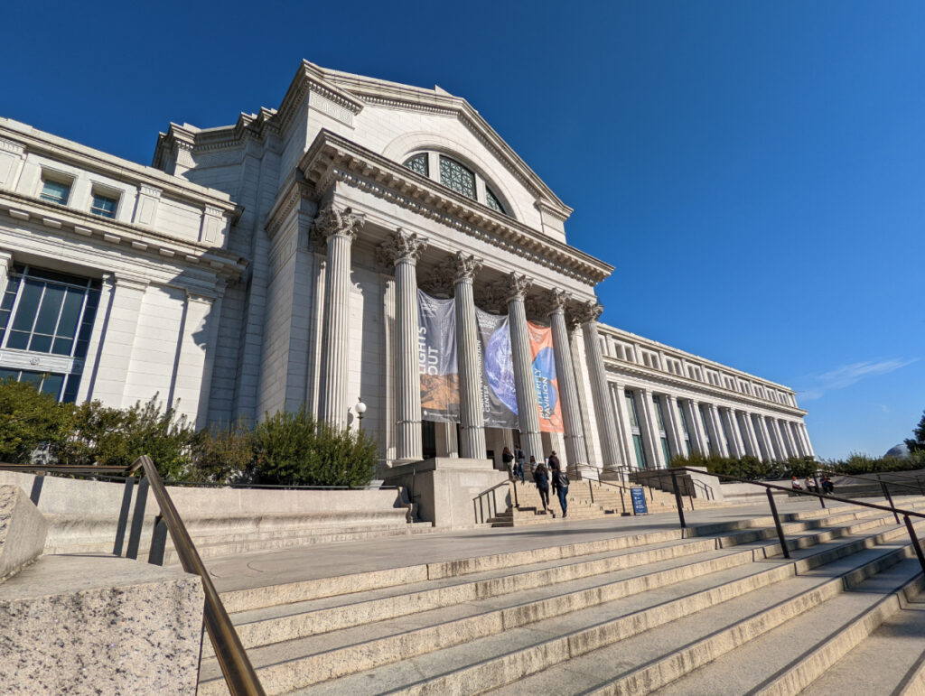 Front entrance of a museum with visitors walking up steps