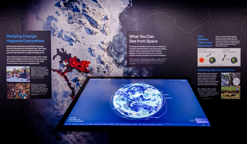 A touch screen showing Earth orbited by satellites