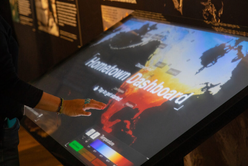 A person reaches out to tap a touchscreen that reads “Hometown Dashboard.”