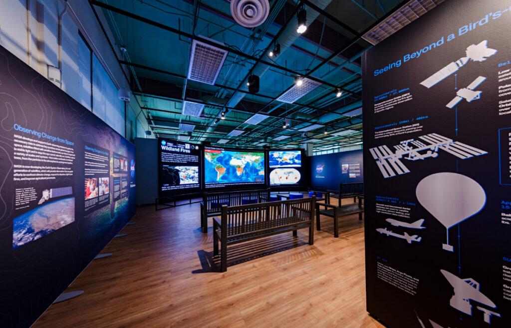 A seating area with benches in front of a large digital wall display