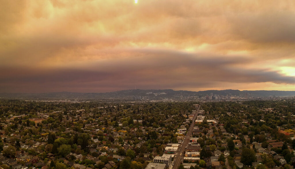 Humo y nubes teñidos de naranja cuelgan bajos sobre el paisaje de Portland, Oregón.