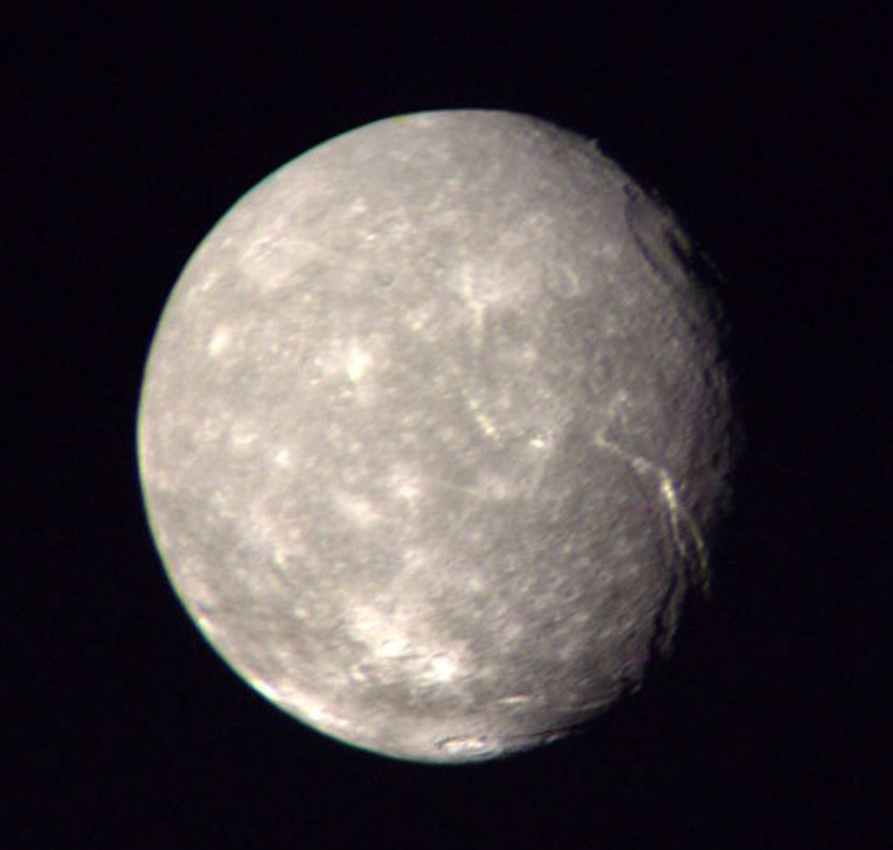 The surface of Titania, a grayish moon of Uranus, marked by bright cracks and circles