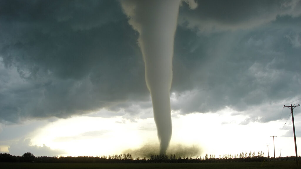 A gray funnel cloud touching Earth’s surface