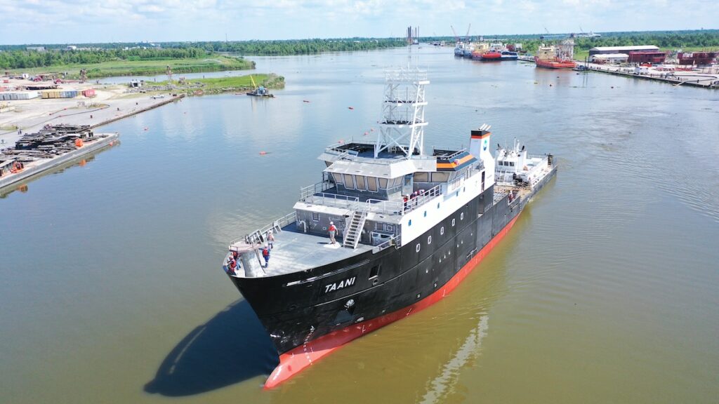 A large blue research vessel floats in a channel.