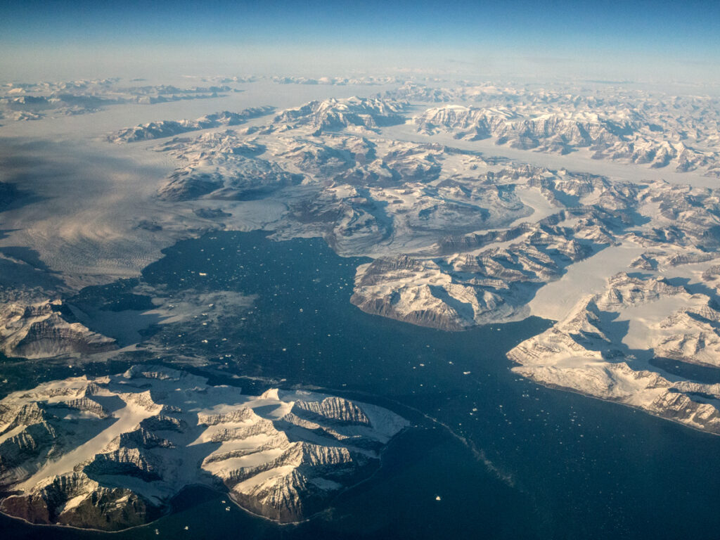 Aerial view of snow-covered mountains, glaciers, and a fjord along the southeastern coast of Greenland