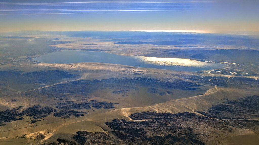 Aerial view of a large, flat body of water among some mountain ranges