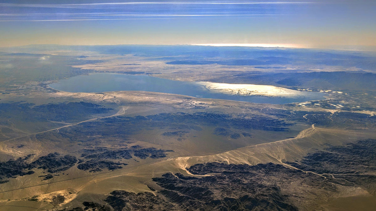 Aerial view of a large, flat body of water among some mountain ranges